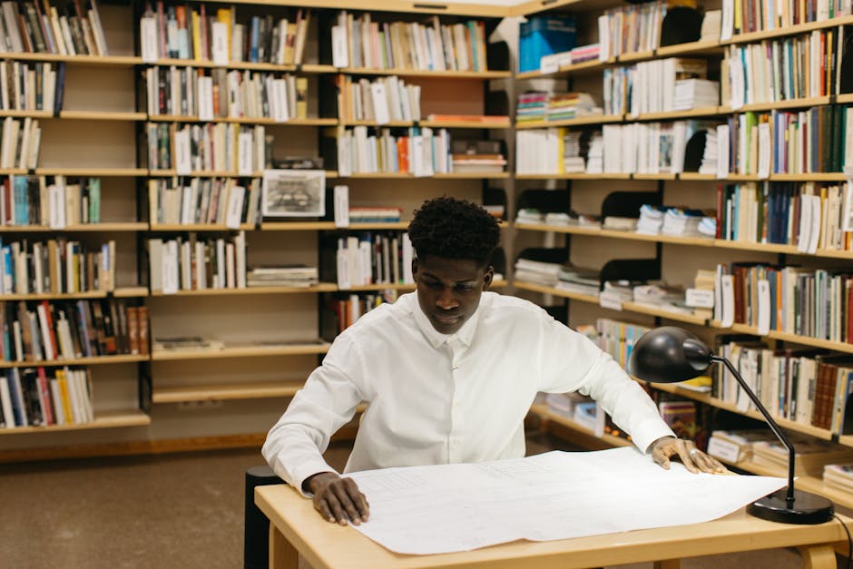 Architect reviewing blueprints in a library workspace, showcasing focused creativity.